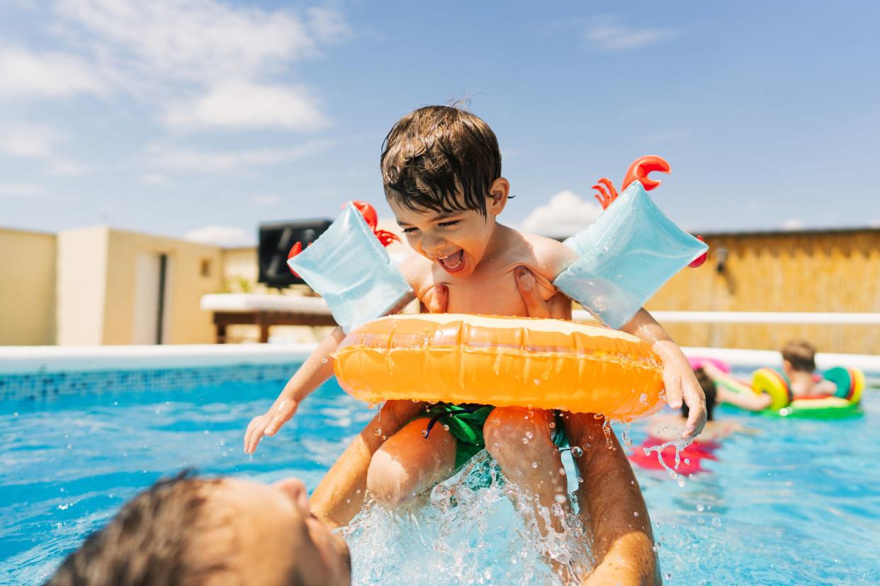 Photo of a little boy having fun with his father while swimming in the pool.