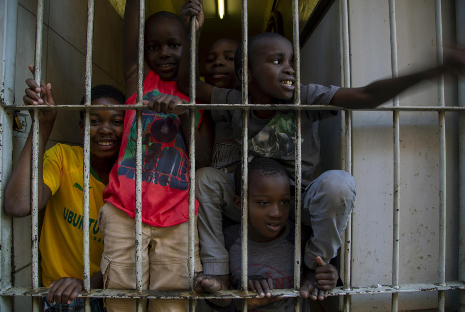 Children look out from a security gate of their flat, during a lockdown to help curb the spread of the new coronavirus in Johannesburg, South Africa, Tuesday, April 7, 2020. South Africa and more than half of Africa's 54 countries have imposed lockdowns, curfews, travel bans or other restrictions to try to contain the spread of COVID-19. The new coronavirus causes mild or moderate symptoms for most people, but for some, especially older adults and people with existing health problems, it can cause more severe illness or death. (AP Photo/Themba Hadebe)
