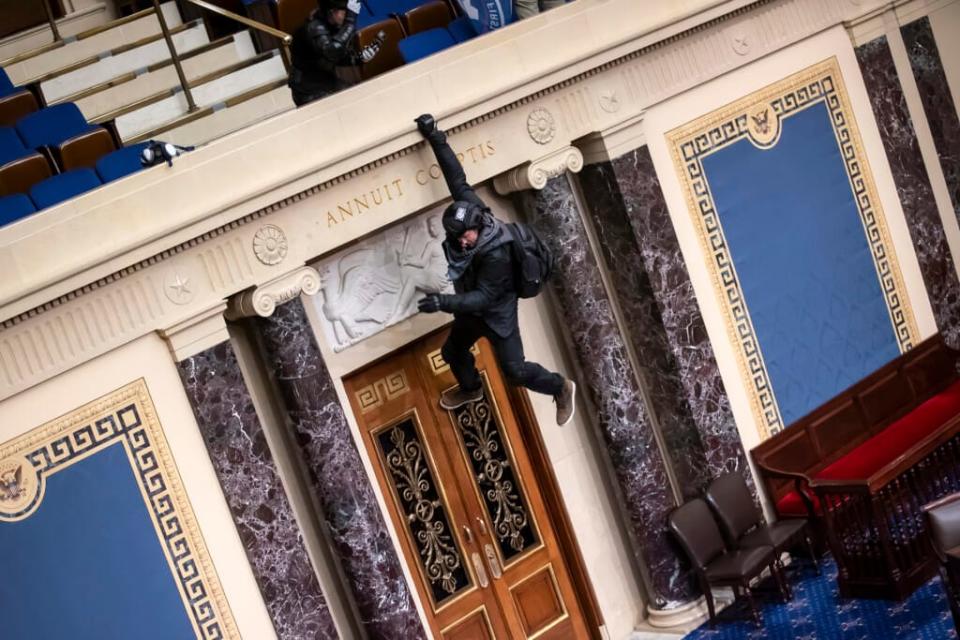 A protester is seen hanging from the balcony in the Senate Chamber on January 06, 2021 in Washington, DC. (Photo by Win McNamee/Getty Images)