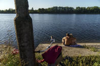 A couple embrace after cooling off in a lake in Sloviansk, Donetsk region, eastern Ukraine, Saturday, Aug. 6, 2022. While the city's remaining population has adapted to a new way of life without running water, local officials warn that the coming of winter could set the stage for a humanitarian crisis. (AP Photo/David Goldman)