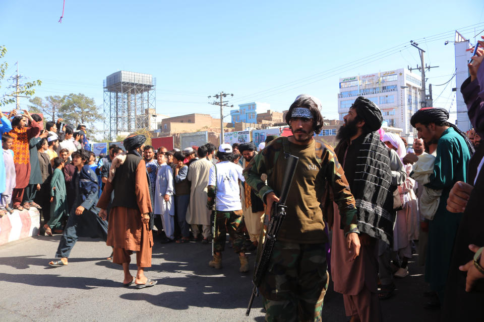 CORRECTS DAY TO SEPT 25 -People gather in the main square of Herat city in western Afghanistan, where the Taliban hanged a dead body from a crane, on Saturday Sept. 25, 2021. A witness told The Associated Press that the bodies of four men were brought to the main square and three of them were moved to other parts of the city for public display. The Taliban announced in the square that the four were caught taking part in a kidnapping and were killed by police. (AP Photo)