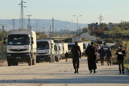 Rebel fighters walk past a Syrian Arab Red Crescent aid convoy heading towards the villages of al-Foua and Kefraya in Idlib province, Syria March 17, 2016. REUTERS/Ammar Abdullah