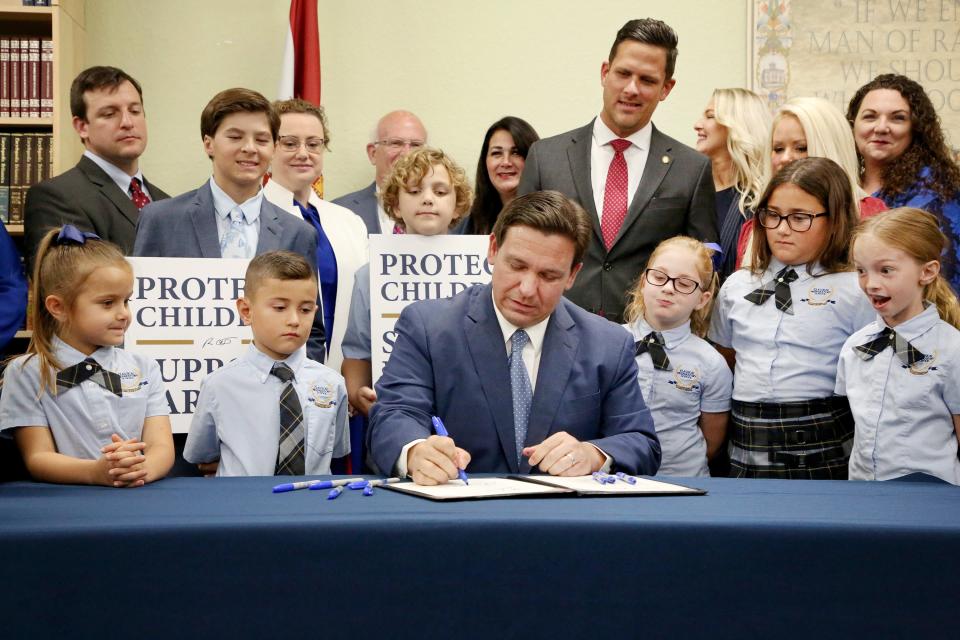 Gov. Ron DeSantis signs the Parental Rights in Education, aka the Don't Say Gay bill, flanked by elementary school students during a news conference on Monday, March 28, 2022, at Classical Preparatory school in Shady Hills. (Douglas R. Clifford/Tampa Bay Times via ZUMA Press Wire)