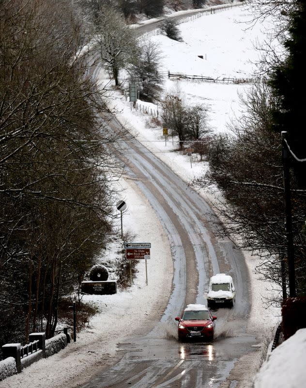 Cars drive along a snow covered flooded road that fell overnight from Storm Arwen, in Leek
