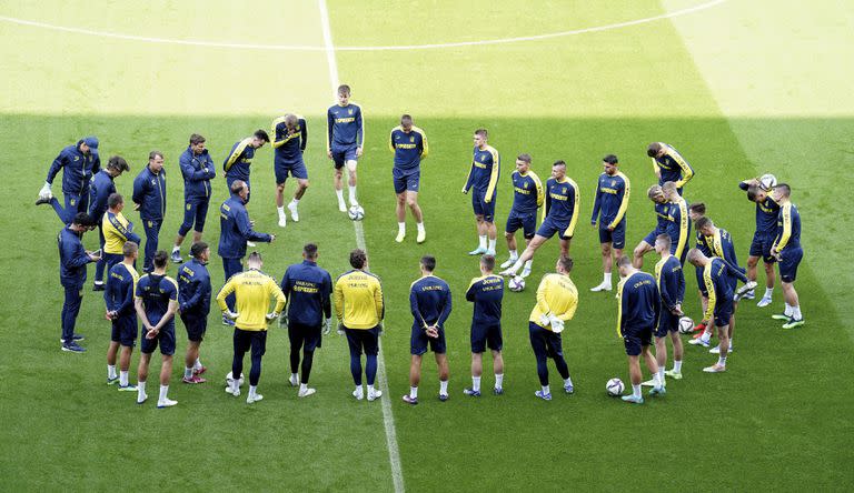 Los jugadores ucranianos forman un círculo durante un entrenamiento en el estadio Cardiff City en Cardiff, Gales, sábado 4 de junio de 2022. Ucrania enfrenta a Gales el domingo por la clasificación al Mundial de Qatar. (Mike Egerton/PA via AP)