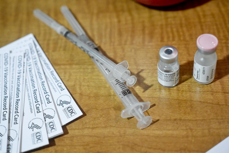 A COVID-19 vaccination record card, syringes and a vial of saline