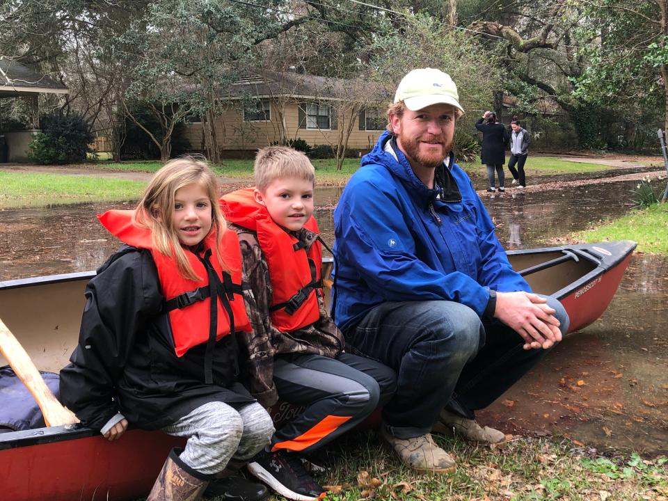 Nate Green and his children, Owen, 8, and Anna Kate, 6, use a canoe to navigate the streets of Jackson, Miss., on Feb. 16.