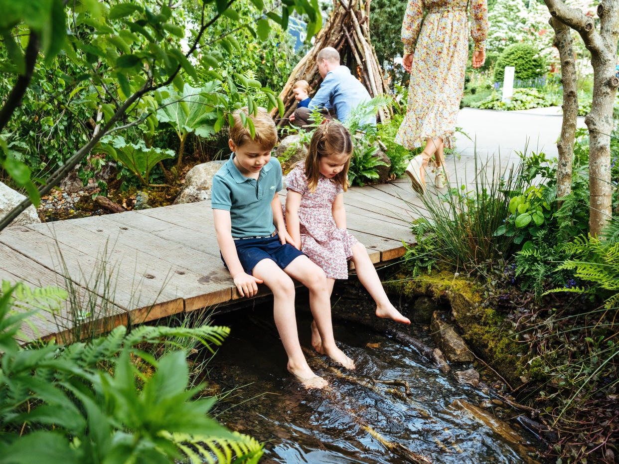 Prince George and Princess Charlotte dip their feet in the garden's pond during their first visit to the garden on Sunday [Photo: Matt Porteous]