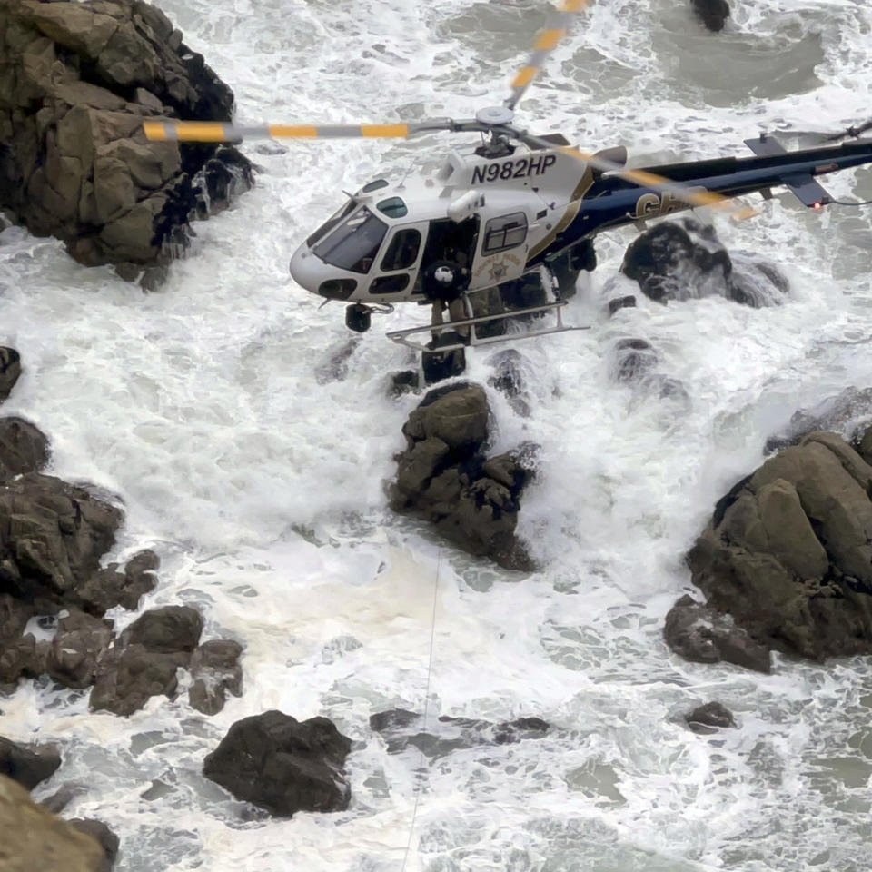 This image from video provided by San Mateo County Sheriff's Office shows a helicopter rescue after a Tesla plunged off a Northern California cliff along the Pacific Coast Highway, Monday, Jan. 2, 2023, near an area known as Devil's Slide, leaving four people in critical condition, a fire official said. (San Mateo County Sheriff's Office via AP)