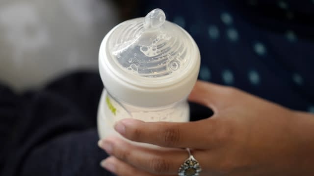 A mom holds a baby bottle.