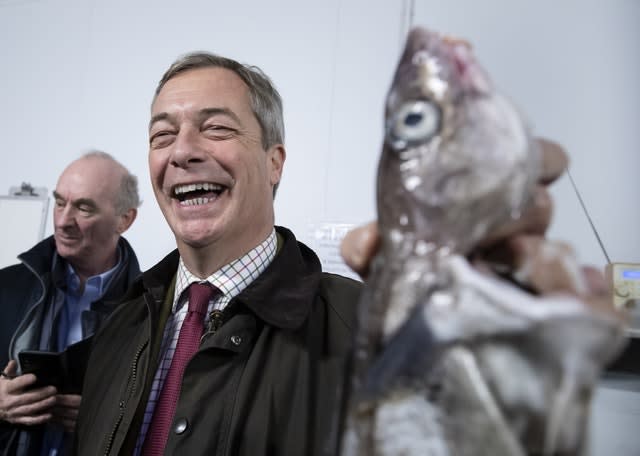 Nigel Farage holds a fish during a stop at the Grimsby Seafood Village