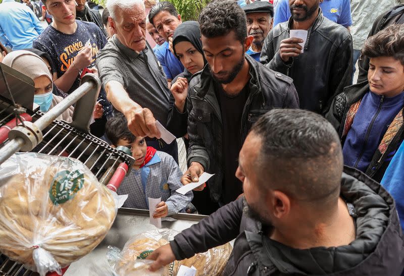 People queue to buy bread outside a bakery in Beirut