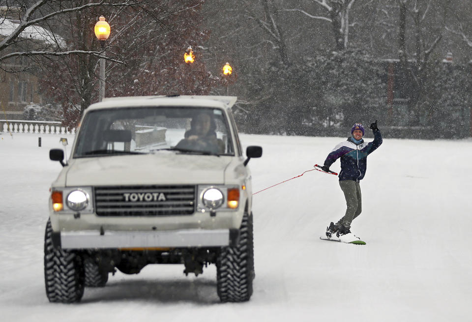 Brian Bowen drags his friend Eric Andries down a street in Overton Park in Memphis, Tenn., Wednesday, Feb. 17, 2021. (Jim Weber/Daily Memphian via AP)