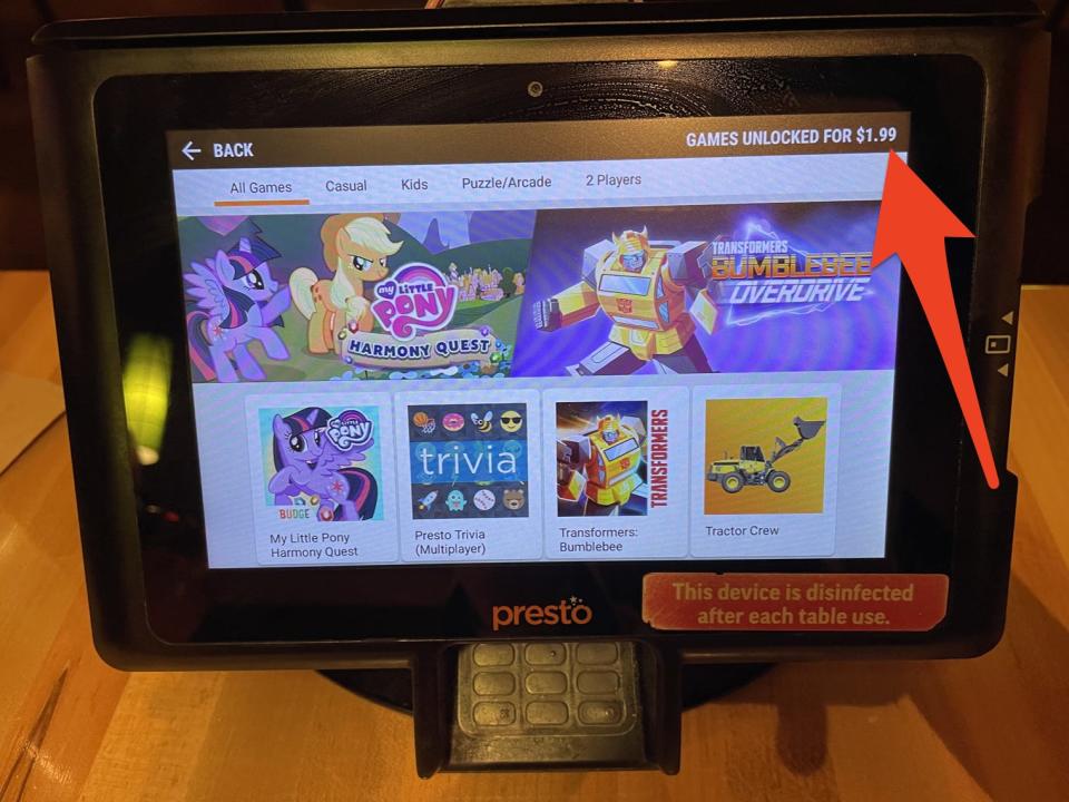 A tablet with games on it with a red arrow pointing to small text that says "Games unlocked for $1.99"