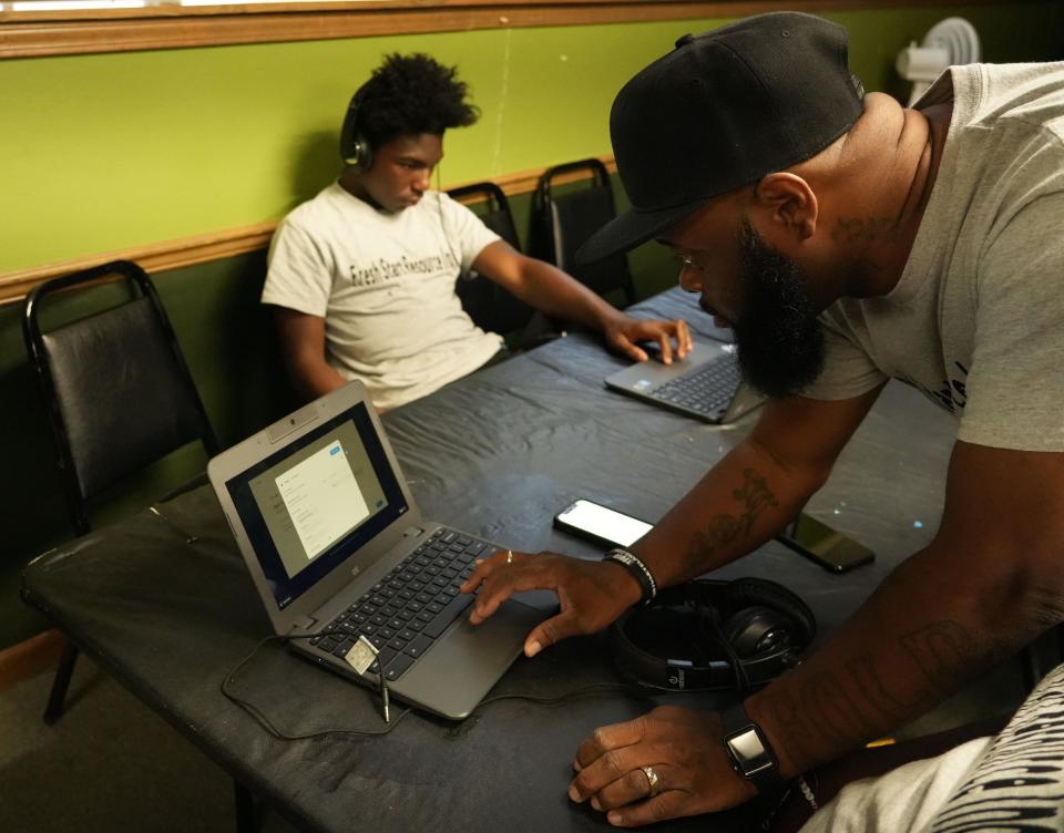 Dynel Fitzpatrick helps Joseph Abernathy, 15, off screen, do computer work while Joseph Williams, background, also works on a computer June 24, 2022, in Indianapolis. Fitzpatrick leads an educational workshop through his program Fresh Start Resource Indy, working to improve the lives of the city's youth.