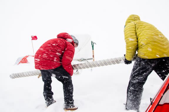 Scientists removing an ice core drill amid inclement weather.