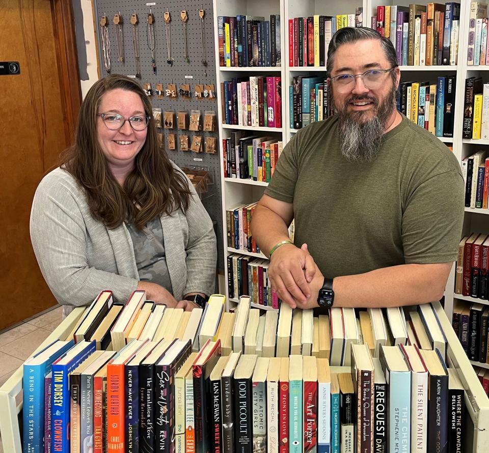 Crystal Bessler, owner of Birch Tree Bookery, stands with her husband Justin behind a library cart full of used books. The couple opened the bookstore in May and have started to bring together a community of booklovers in the area.