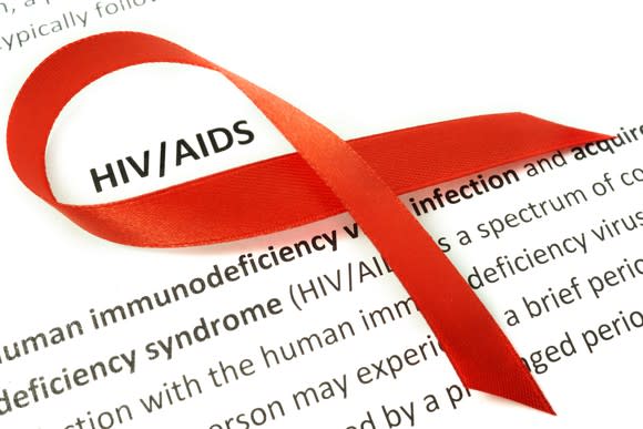 Red ribbon on a paper with the definition of HIV/AIDS