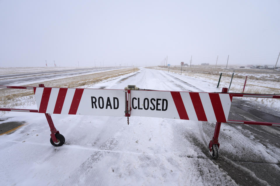 A road closed sign hangs on a shuttered gate to prevent traffic from entering the eastbound lanes of Interstate 70 at East Airpark Road Tuesday, Dec. 13, 2022, in Aurora, Colo. A massive winter storm has closed roads throughout northeast Colorado. (AP Photo/David Zalubowski)