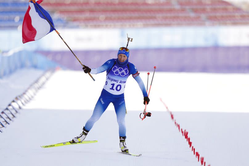 FILE: Justine Braisaz-Bouchet of France approaches the finish line during the women's 12.5-kilometer mass start biathlon at the 2022 Winter Olympics