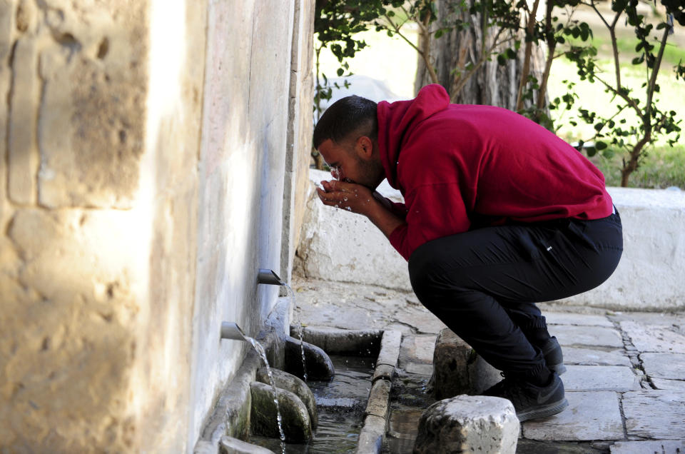 A man drinks water from a water source in Sidi Bou Said, north of Tunis, Wednesday, April 12, 2023. Tunisians are on the frontlines of a battle against an increasingly severe drought, now in its fifth year in the North African country, with the government issuing a sudden order to its population to ration their water usage for six months — or risk fines or jail. (AP Photo/Hassene Dridi)