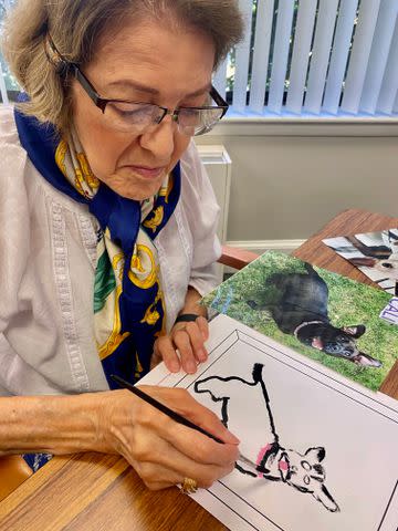 <p>Courtesy of Draw For Paws</p> Hilda Shaffer painting a portrait of Cali the dog