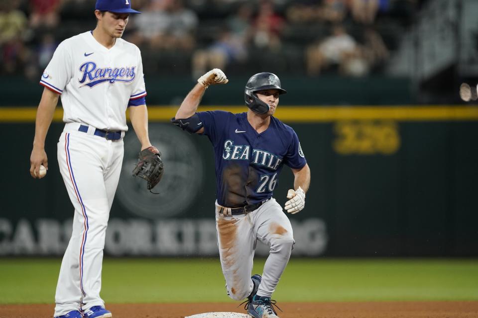 Seattle Mariners' Adam Frazier (26) celebrates his double as Texas Rangers shortstop Corey Seager, left, walks past in the fourth inning of a baseball game, Saturday, July 16, 2022, in Arlington, Texas. (AP Photo/Tony Gutierrez)