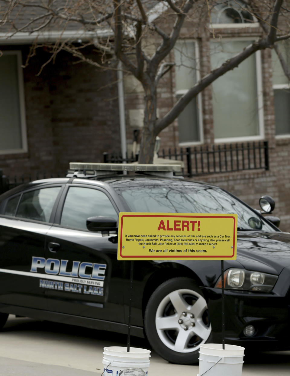 A warning sign and a police officer's vehicle are stationed at Walt Gilmore's home on Thursday, March 21, 2019. The Utah family has become the victim of extreme stalking involving unwanted service providers repeatedly being sent to their home, according to the homeowner and police. (Laura Seitz/The Deseret News via AP)