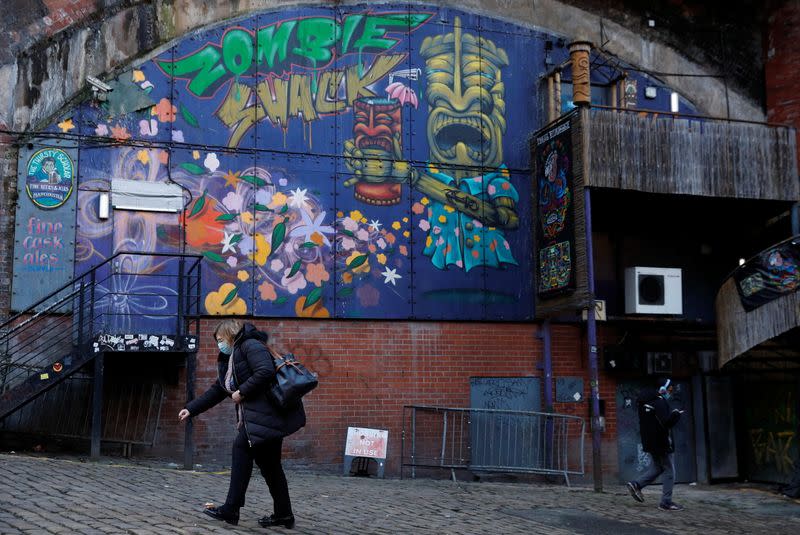 A woman in a face mask walks past the closed Zombie Shack nightclub in Manchester