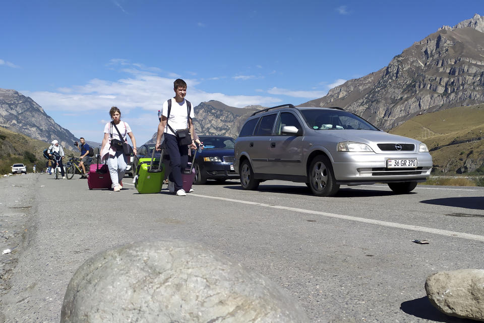 People walk toward the border crossing at Verkhny Lars between Georgia and Russia leaving Chmi, North Ossetia - Alania Republic, Russia, Thursday, Sept. 29, 2022. Long lines of vehicles have formed at a border crossing between Russia's North Ossetia region and Georgia after Moscow announced a partial military mobilization. A day after President Vladimir Putin ordered a partial mobilization to bolster his troops in Ukraine, many Russians are leaving their homes. (AP Photo)