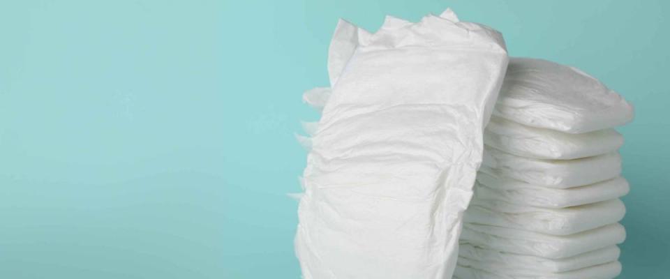 Stack of diapers on light blue background. Space for text