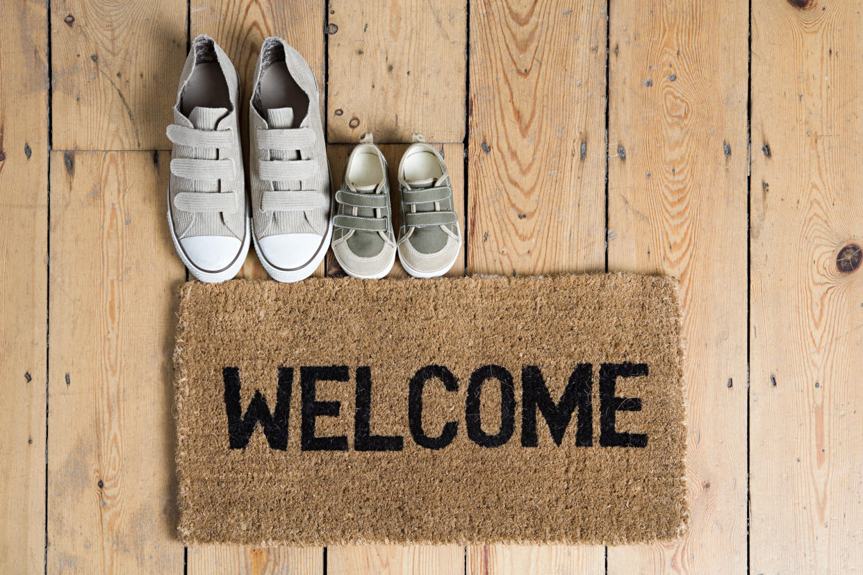 A pair of training shoes placed next to a welcome mat