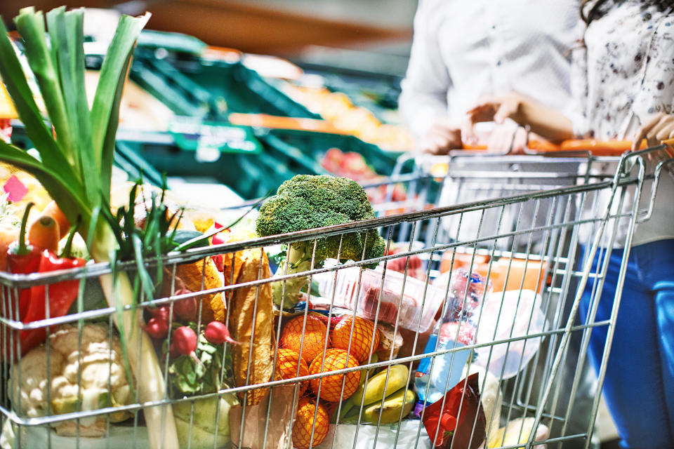 Unrecognizable young couple with a full shopping cart of groceries at a convenience store.