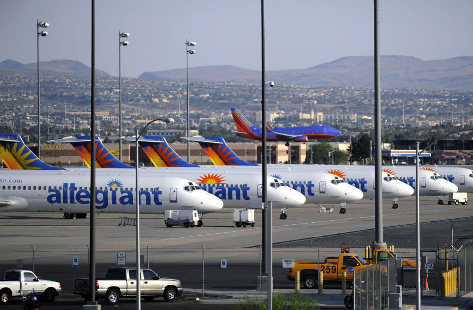 In this Thursday, May 9, 2013, photo, a Southwest airliner comes in for a landing as a row of Allegiant Air jets are parked at McCarran International Airport in Las Vegas. While other U.S. airlines have struggled with the ups and downs of the economy and oil prices, tiny Allegiant Air has been profitable for 10 straight years. (AP Photo/David Becker)