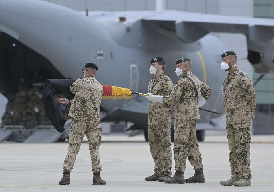 Brigadier General Ansgar Meyer , left, the last commander of the Bundeswehr in Afghanistan, furls the troop flag in front of the Luftwaffe's Airbus A400M transport aircraft in Wunstorf, Germany, Wednesday, June 30, 2021. The last soldiers of the German Afghanistan mission have arrived at the air base in Lower Saxony. The mission had ended the previous evening after almost 20 years. The soldiers had been flown out with four military planes from the field camp in Masar-i-Sharif in the north of Afghanistan. (Hauke-Christian Dittrich/Pool via AP)