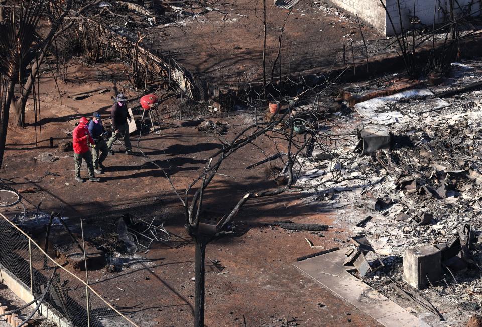 In an aerial view, search and rescue crews walk through a neighborhood that was destroyed by a wildfire on August 11, 2023 in Lahaina, Hawaii. Dozens of people were killed and thousands were displaced after a wind-driven wildfire devastated the town of Lahaina on Tuesday. Crews are continuing to search for missing people.