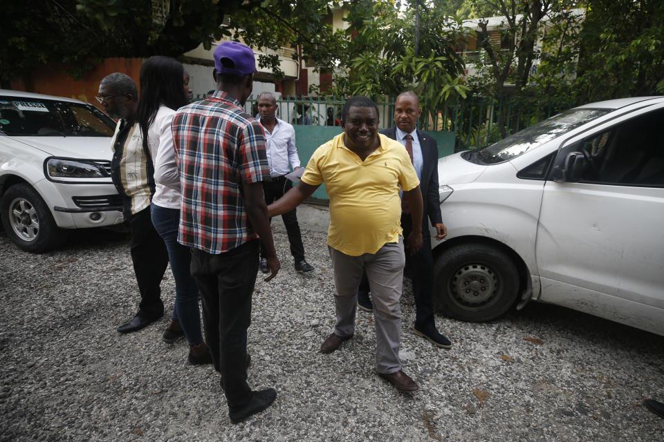 André Michel, center, is trailed by Senator Nenel Cassy as he says hello to journalists following a press conference to announce plans for a massive protest march to the United Nations headquarters the following day, in Port-au-Prince, Haiti, Thursday, Oct. 3, 2019. Among those leading the protests is an opposition coalition called the Democratic and Popular Sector, whose members include attorney Michel, one of 70 candidates who ran in the 2015 presidential elections.(AP Photo/Rebecca Blackwell)