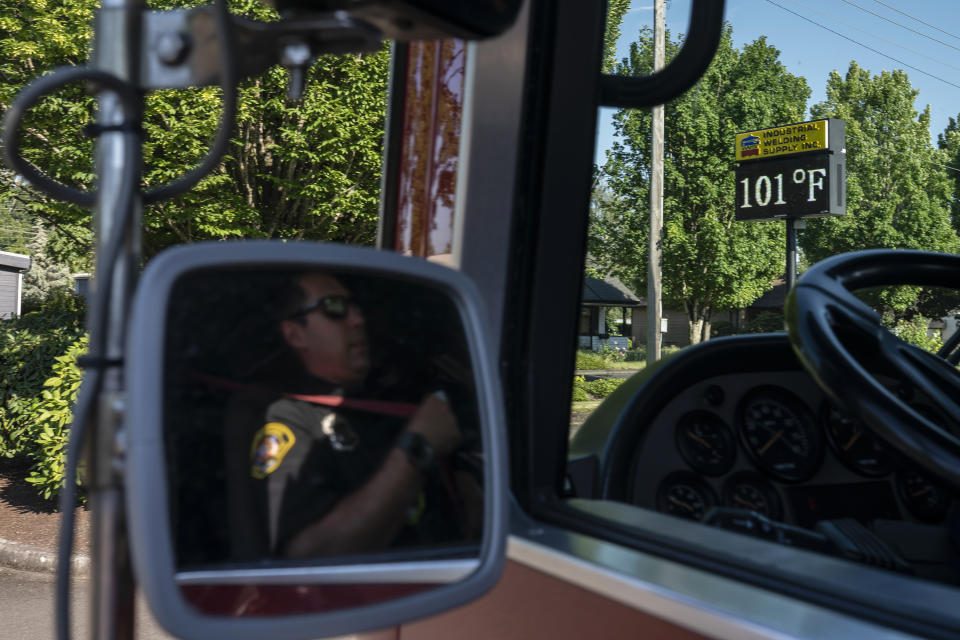 Cody Miller, with the Salem Fire Department, waits in his truck near a digital sign tracking the day's temperatures during a heat wave, Saturday, June 26, 2021, in Salem, Ore. (AP Photo/Nathan Howard)