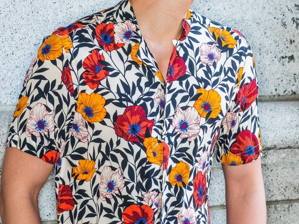 man wearing a floral print short sleeve button down with a camp collar over jeans