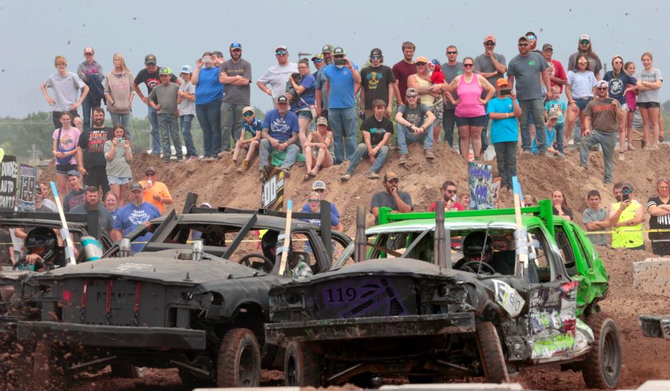 A crowd stands on a large hill of dirt watching the action as cars crash into each other during TNT Demolition Derby's Wexford Warzone Weekend at Wexford County Fairgrounds in Cadillac on Saturday, June 10, 2023.
Over 2,500 fans came to the event to watch the various categories of cars bump and run and some crash into each other during the two day event.