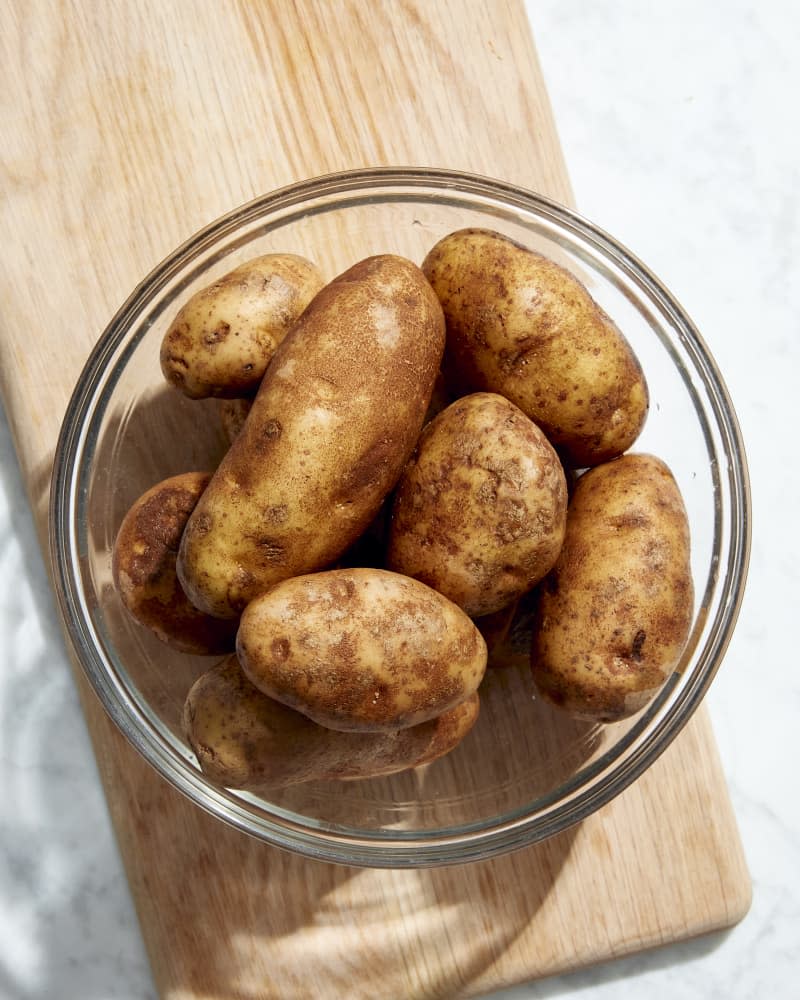 whole potatoes on cutting board in bowl