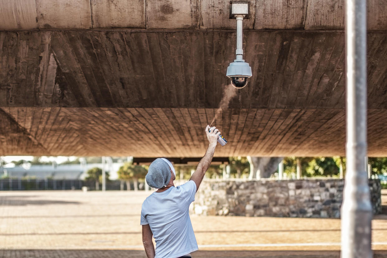 Spraying graffiti on security camera Getty Images/Westend61