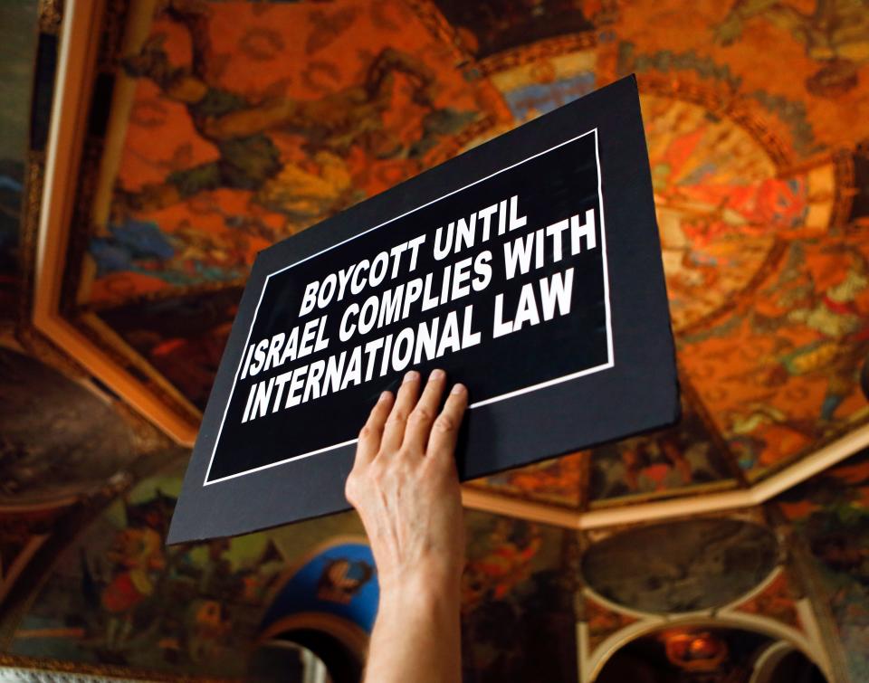 A man holds a sign during a rally in the War Room at the state Capitol on Wednesday, June 15, 2016, in Albany, N.Y. Critics of Israel's treatment of Palestinians protested Gov. Andrew Cuomo's executive order prohibiting state investments in any company that supports a boycott of Israel.