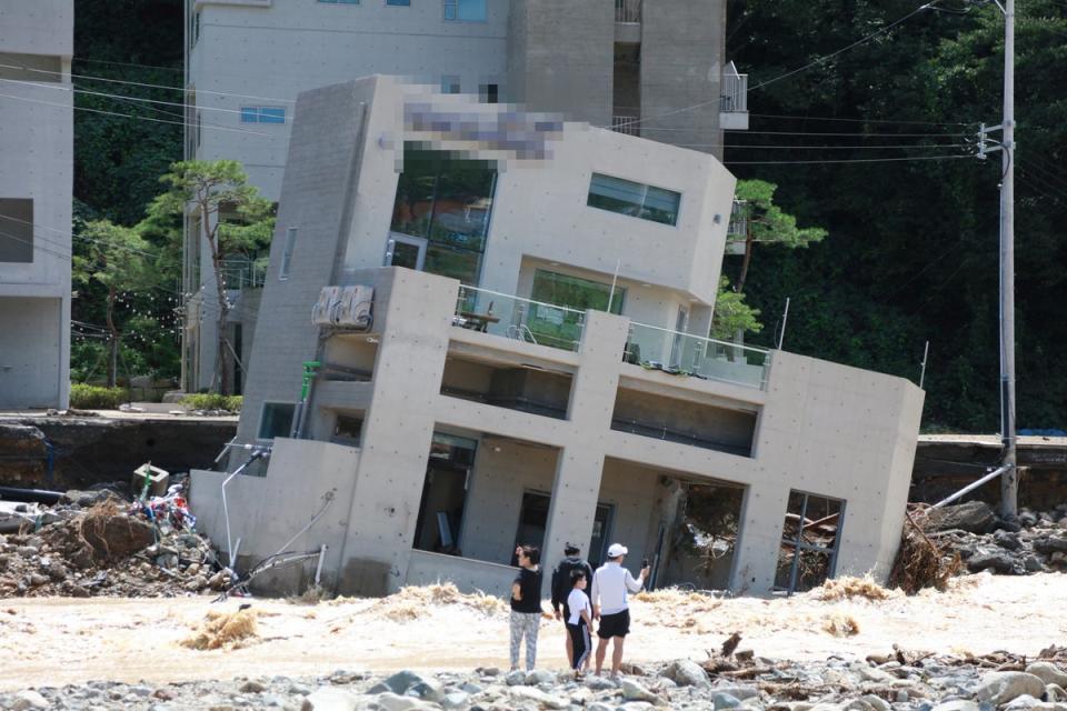 People stand in front of a collapsed building after Typhoon Hinnamnor made landfall in Pohang (REUTERS)