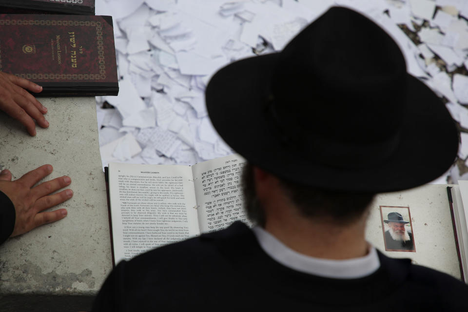 In this July 2, 2019 photo, a picture of Rabbi Menachem M. Schneerson rests on the edge of his grave site where people pray in the Queens borough of New York. Schneerson led Chabad-Lubavitch for more than four decades as the seventh rebbe, or spiritual leader, following the death of his father-in-law, whom he is buried next to at the Montefiore Cemetery in Cambria Heights in eastern Queens. His wife’s and mother-in-law’s graves are a short distance away. (AP Photo/Seth Wenig)