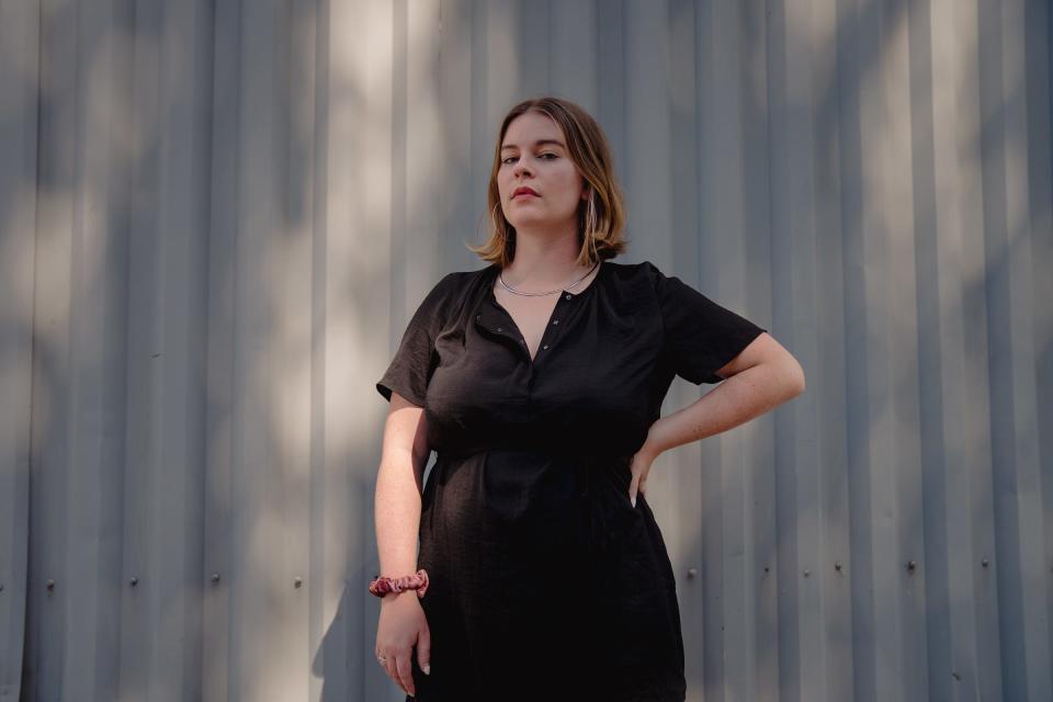 Tori Dunlap wearing a black short-sleeve top with silver hoop earrings and a necklace.