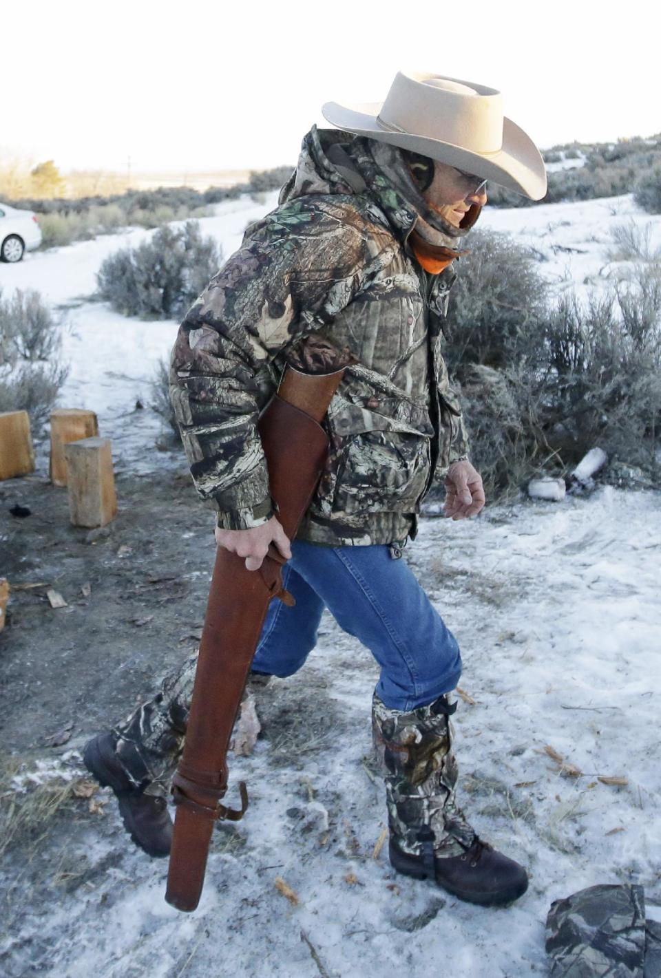 FILE--In this Jan. 6, 2016, file photo, Arizona rancher LaVoy Finicum carries his rifle after standing guard all night at the Malheur National Wildlife Refuge near Burns, Ore. Finicum's widow, Jeanette Finicum, and their children are planning to hold a meeting in John Day, Ore., Jan. 28, 2017, in an effort to continue with his mission. (AP photo/Rick Bowmer, file)