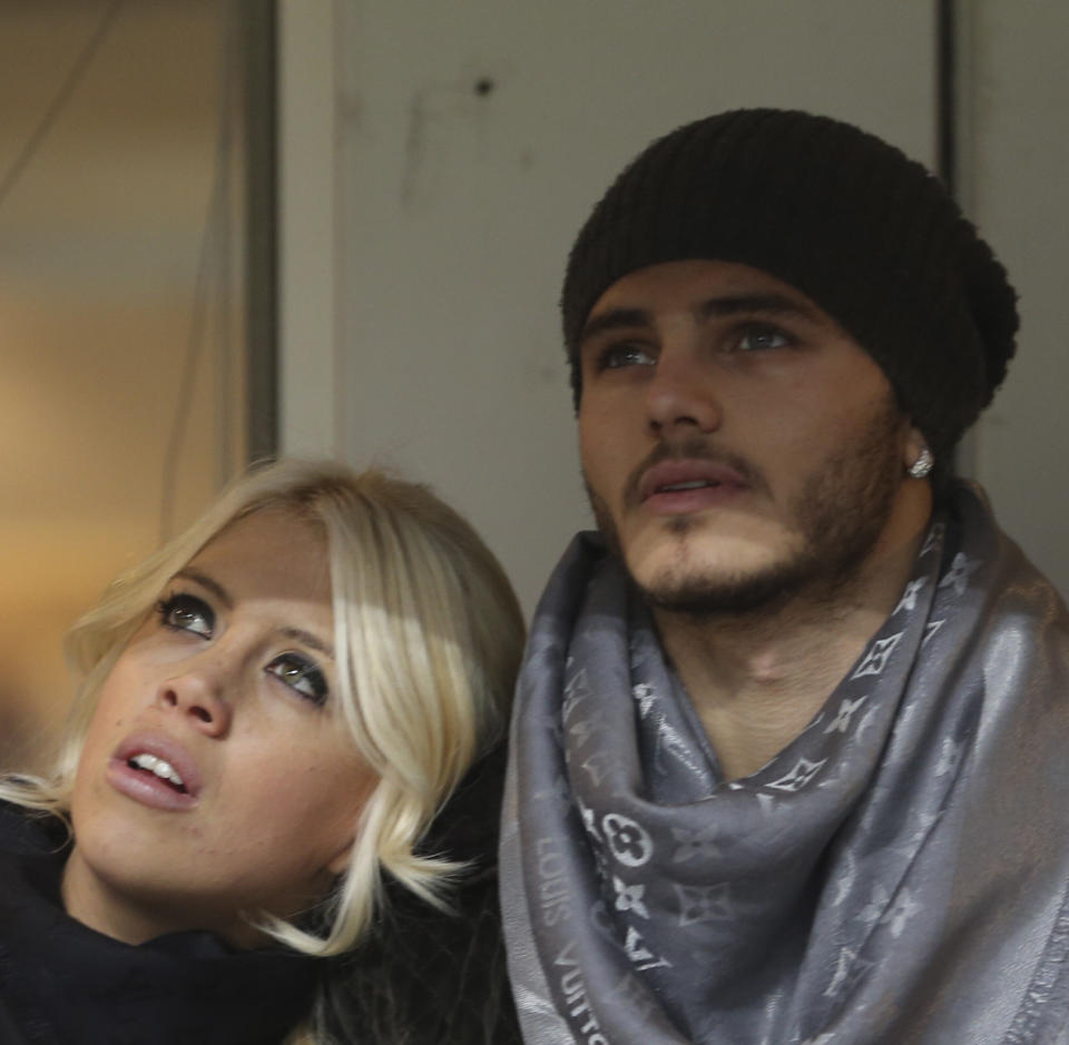 FILE - In this Jan. 13, 2014 file photo, Inter Milan forward Mauro Icardi, of Argentina, is flanked by his wife Wanda Nara as they sit in the stands prior to a Serie A soccer match between Inter Milan and Chievo, at the San Siro stadium in Milan, Italy, Monday, Jan.13, 2014. Two months ago, Mauro Icardi was one of Inter Milan's favored players, on Thursday, Feb. 14, 2019, he was training with just a handful of teammates at their training ground after a rapid fall from grace after Icardi and Inter have been in protracted talks over renewing his contract, which expires in 2021, with agent-wife Wanda Nara being particularly outspoken over the past month. (AP Photo/Luca Bruno)