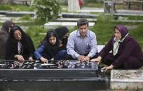 In this picture taken on Monday, April 28, 2014, Iranian man Abdolghani Hosseinzadeh, second right, his wife Samereh Alinejad, left, and his daughter Fatemeh, second left, pray at the grave of the family's sons Amir Hossein and Abdollah in a cemetery in the city of Royan about 146 miles (235 kilometers) north of the capital Tehran, Iran. Amir Hossein was killed in a motorcycle crash and Abdollah was killed in a street brawl. Abdolghani's sister prays at right. Alinejad tells The Associated Press that she had felt she could never live with herself if the man who killed her son Abdollah were spared. But in the last moment, she pardoned him in an act that has made her a hero in her hometown, where banners in the streets praise her family’s mercy. (AP Photo/Vahid Salemi)