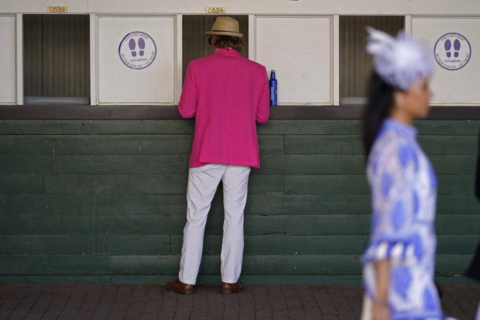 A man places a bet before the 147th running of the Kentucky Derby at Churchill Downs, Saturday, May 1, 2021, in Louisville, Ky. (AP Photo/Charlie Riedel)